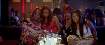Movie still from “Beauty Shop” (2005), directed by Bille Woodruff – A group of women sitting at a table with wine glasses; Medium shot, High angle