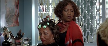 Movie still from “Beauty Shop” (2005), directed by Bille Woodruff – Two women with hair curlers on their heads; Medium shot, Over the shoulder angle