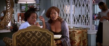 Movie still from “Beauty Shop” (2005), directed by Bille Woodruff – Two women sitting at a table with a plate in front of them; Medium shot, Over the shoulder angle