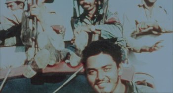 Movie still from “Before Night Falls” (2000), directed by Julian Schnabel – A man smiling for the camera while sitting next to another man; Extreme Close Up shot, Overhead angle