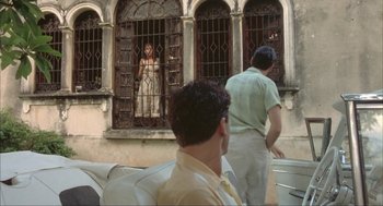 Movie still from “Before Night Falls” (2000), directed by Julian Schnabel – Two men are looking out of a window at a statue; Wide shot, Over the shoulder angle