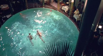 Movie still from “Before Night Falls” (2000), directed by Julian Schnabel – Two people swimming in an indoor swimming pool; Extreme Wide shot, High angle