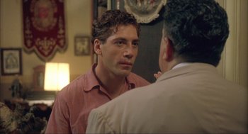 Movie still from “Before Night Falls” (2000), directed by Julian Schnabel – A man looking into a mirror while standing next to another man; Close Up shot, Over the shoulder angle