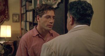 Movie still from “Before Night Falls” (2000), directed by Julian Schnabel – A man in a red shirt talking to another man in a tan jacket; Close Up shot, Over the shoulder angle