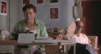 Movie still from “Before Night Falls” (2000), directed by Julian Schnabel – A man sitting at a table in front of a woman; Medium shot, Low angle