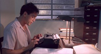 Movie still from “Before Night Falls” (2000), directed by Julian Schnabel – A man sitting in front of an old fashioned typewriter; Medium shot, Low angle