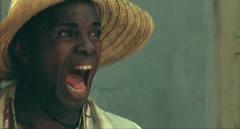 Movie still from “Before Night Falls” (2000), directed by Julian Schnabel – A man wearing a straw hat with his mouth wide open; Close Up shot, Low angle