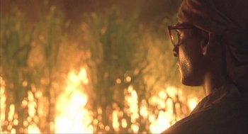 Movie still from “Before Night Falls” (2000), directed by Julian Schnabel – A man wearing glasses is looking at a fire; Close Up shot, Low angle