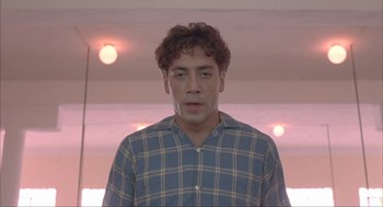 Movie still from “Before Night Falls” (2000), directed by Julian Schnabel – A young man in a plaid shirt is looking at the camera; Close Up shot, Low angle