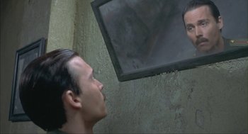 Movie still from “Before Night Falls” (2000), directed by Julian Schnabel – A man looking at himself in the mirror; Close Up shot, Over the shoulder angle