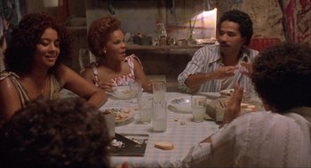 Movie still from “Before Night Falls” (2000), directed by Julian Schnabel – A group of people sitting around a table eating food; Medium shot, High angle