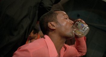 Movie still from “Before Night Falls” (2000), directed by Julian Schnabel – A man in a pink shirt drinking a glass of water; Close Up shot, Low angle