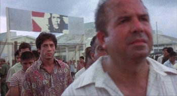 Movie still from “Before Night Falls” (2000), directed by Julian Schnabel – A group of men standing next to each other in a crowd; Medium shot, Low angle