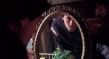 Movie still from “Before Night Falls” (2000), directed by Julian Schnabel – A man looking at himself in a mirror; Close Up shot, Low angle