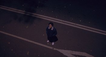 Movie still from “Before Night Falls” (2000), directed by Julian Schnabel – A person standing in a parking lot at night; Extreme Wide shot, Overhead angle