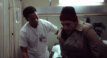 Movie still from “Before Night Falls” (2000), directed by Julian Schnabel – A man in a lab coat is looking at another man in a lab coat; Medium shot, Low angle