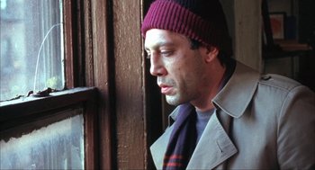 Movie still from “Before Night Falls” (2000), directed by Julian Schnabel – A man wearing a hat and a scarf looking out of a window; Close Up shot, Low angle