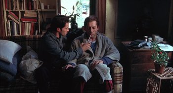 Movie still from “Before Night Falls” (2000), directed by Julian Schnabel – Two men sitting in a living room one is brushing his teeth and the other is brushing his teeth; Medium shot, High angle