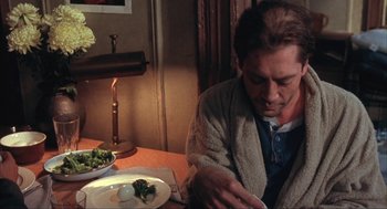 Movie still from “Before Night Falls” (2000), directed by Julian Schnabel – A man sitting at a table with a plate of food; Close Up shot, High angle