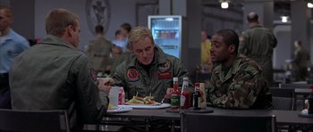 Movie still from “Behind Enemy Lines” (2001), directed by John Moore – A group of people sitting at a table eating food; Medium shot, Over the shoulder angle