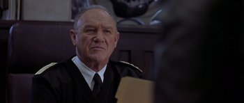 Movie still from “Behind Enemy Lines” (2001), directed by John Moore – An older man wearing a suit and tie looking at the camera; Close Up shot, Low angle