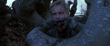 Movie still from “Behind Enemy Lines” (2001), directed by John Moore – A man with a pair of binoculars in his hands; Medium shot, Low angle