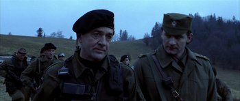 Movie still from “Behind Enemy Lines” (2001), directed by John Moore – Two men in military fatigues are standing in a field; Medium shot, Low angle