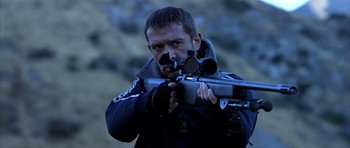 Movie still from “Behind Enemy Lines” (2001), directed by John Moore – A man holding a rifle and aiming it at the camera; Close Up shot, Low angle