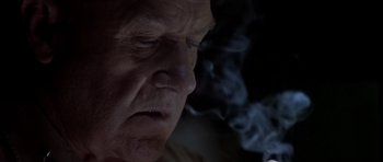 Movie still from “Behind Enemy Lines” (2001), directed by John Moore – An older man is smoking a cigarette in a dimly - lit room; Close Up shot, Low angle