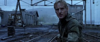 Movie still from “Behind Enemy Lines” (2001), directed by John Moore – A man standing in front of a train track; Close Up shot, Over the shoulder angle