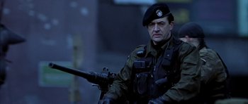 Movie still from “Behind Enemy Lines” (2001), directed by John Moore – A man in a military uniform holding a rifle; Medium shot, Low angle