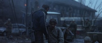 Movie still from “Behind Enemy Lines” (2001), directed by John Moore – A man sitting on the ground next to another man; Medium shot, Over the shoulder angle