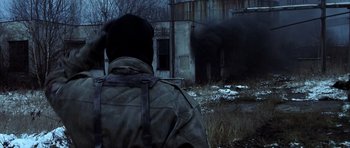 Movie still from “Behind Enemy Lines” (2001), directed by John Moore – A man wearing a jacket and hat looking at an elephant in a field; Medium shot, Over the shoulder angle