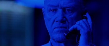 Movie still from “Behind Enemy Lines” (2001), directed by John Moore – An older man talking on a cell phone in front of a blue light; Close Up shot, Low angle
