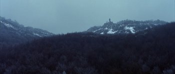 Movie still from “Behind Enemy Lines” (2001), directed by John Moore – A snowy hill with trees in the foreground and a castle in the background; Extreme Wide shot, Low angle