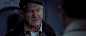 Movie still from “Behind Enemy Lines” (2001), directed by John Moore – An older man wearing a baseball cap and jacket; Close Up shot, Over the shoulder angle