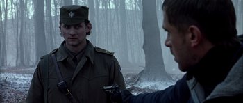Movie still from “Behind Enemy Lines” (2001), directed by John Moore – A man in a military uniform is looking at another man in the woods; Medium shot, Over the shoulder angle