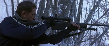Movie still from “Behind Enemy Lines” (2001), directed by John Moore – A man is holding a rifle in the snow; Medium shot, Over the shoulder angle