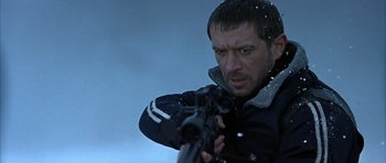 Movie still from “Behind Enemy Lines” (2001), directed by John Moore – A man holding a gun while standing in the snow; Close Up shot, Low angle