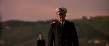 Movie still from “Behind Enemy Lines” (2001), directed by John Moore – A man in a military uniform is walking in front of another man; Medium shot, Low angle