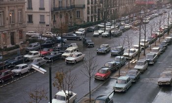 Movie still from “Belle de Jour” (1967), directed by Luis Buñuel – Cars parked on a city street in the rain; Extreme Wide shot, High angle