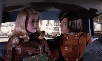 Movie still from “Belle de Jour” (1967), directed by Luis Buñuel – Two women are talking in the back of a car; Medium shot, Over the shoulder angle