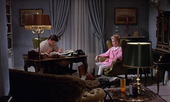 Movie still from “Belle de Jour” (1967), directed by Luis Buñuel – A man and a little girl sitting at a table in a living room; Wide shot, High angle