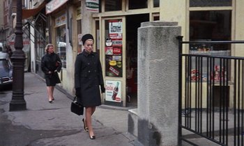 Movie still from “Belle de Jour” (1967), directed by Luis Buñuel – A woman walking down the street with a purse in her hand; Wide shot, High angle