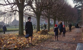 Movie still from “Belle de Jour” (1967), directed by Luis Buñuel – A group of people walking in a park near trees; Extreme Wide shot, High angle