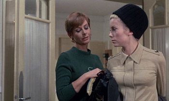 Movie still from “Belle de Jour” (1967), directed by Luis Buñuel – A woman looking at another woman holding a jacket; Medium shot, Over the shoulder angle
