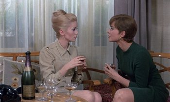 Movie still from “Belle de Jour” (1967), directed by Luis Buñuel – Two women sitting at a table talking to each other; Medium shot, High angle