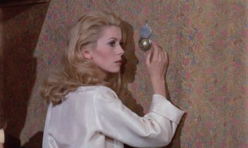 Movie still from “Belle de Jour” (1967), directed by Luis Buñuel – A beautiful blonde haired woman holding a mirror in front of a wall; Medium shot, Overhead angle