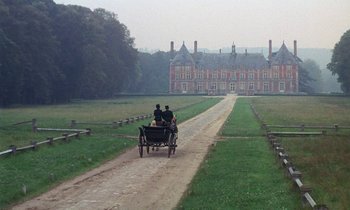 Movie still from “Belle de Jour” (1967), directed by Luis Buñuel – Two people are riding in a horse drawn carriage down a road; Extreme Wide shot, High angle