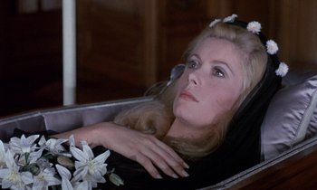 Movie still from “Belle de Jour” (1967), directed by Luis Buñuel – A woman with flowers in her hair sitting in a chair; Close Up shot, High angle